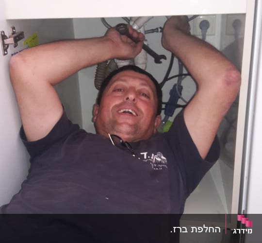 אדם מתקן צנרת מתחת לכיור עם מפתח צינורות